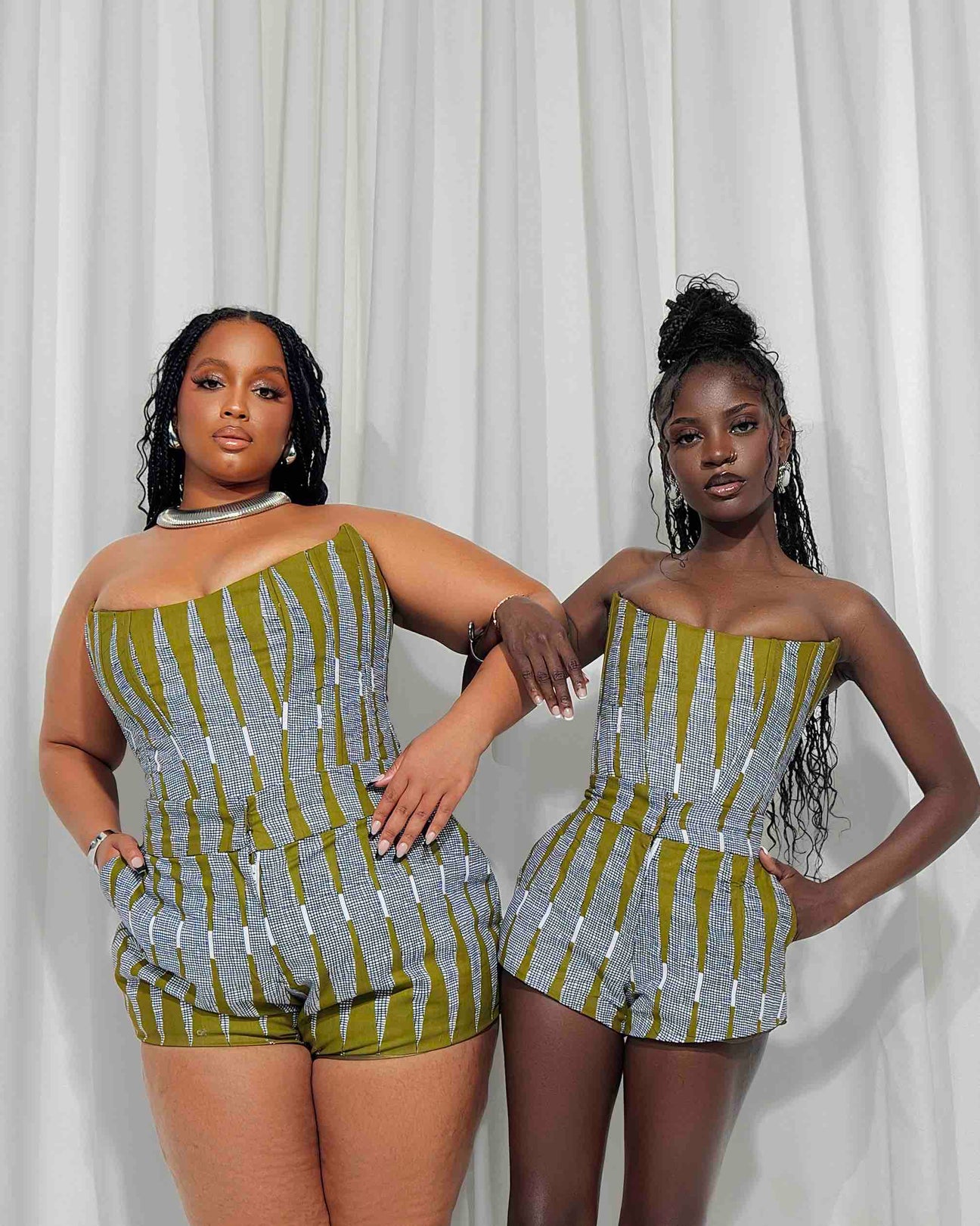 Bold and vibrant African print rompers worn by two stylish young women against a white backdrop.