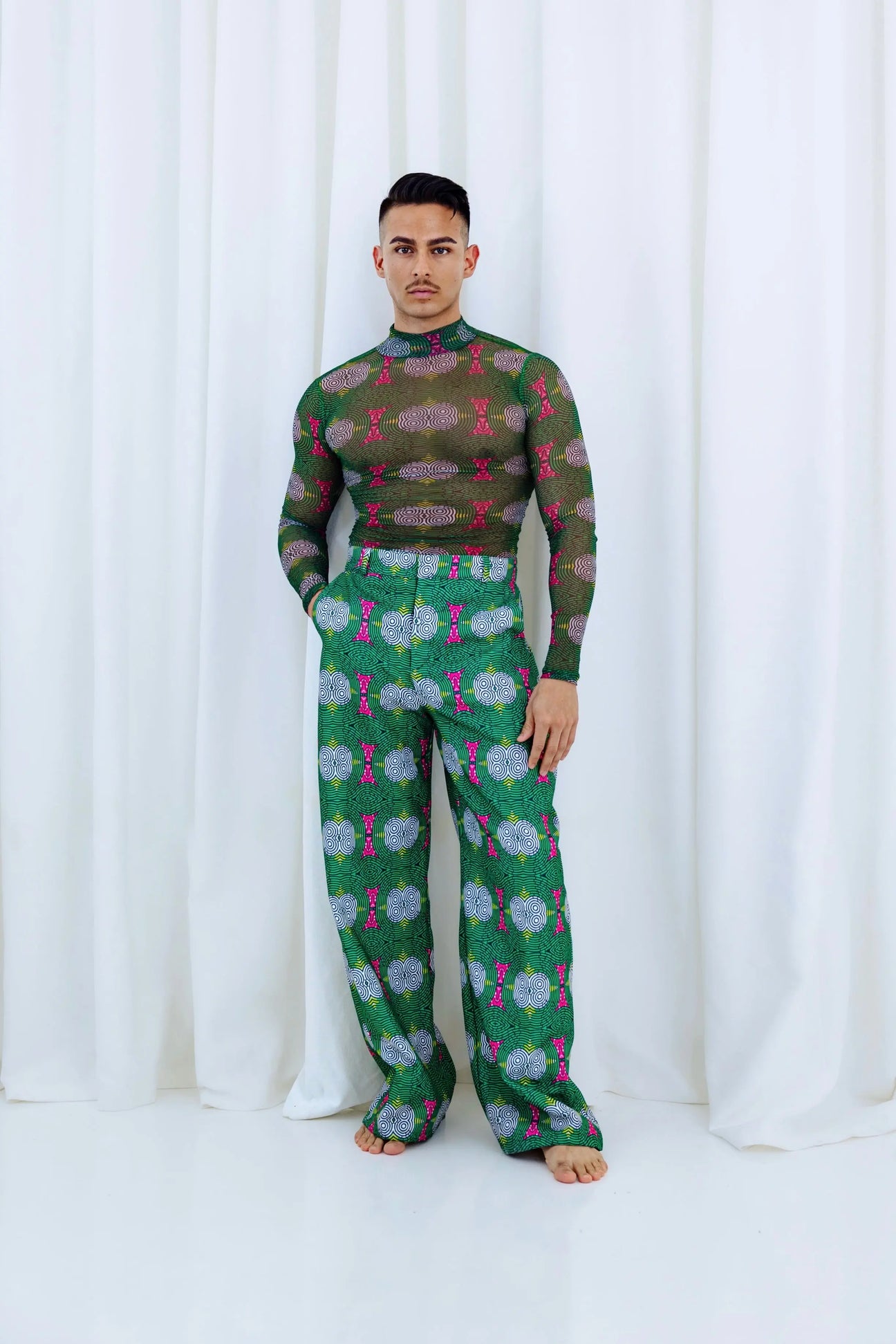 Vibrant green African mesh top with bold floral pattern, paired with matching printed pants, showcasing stylish African-inspired fashion.