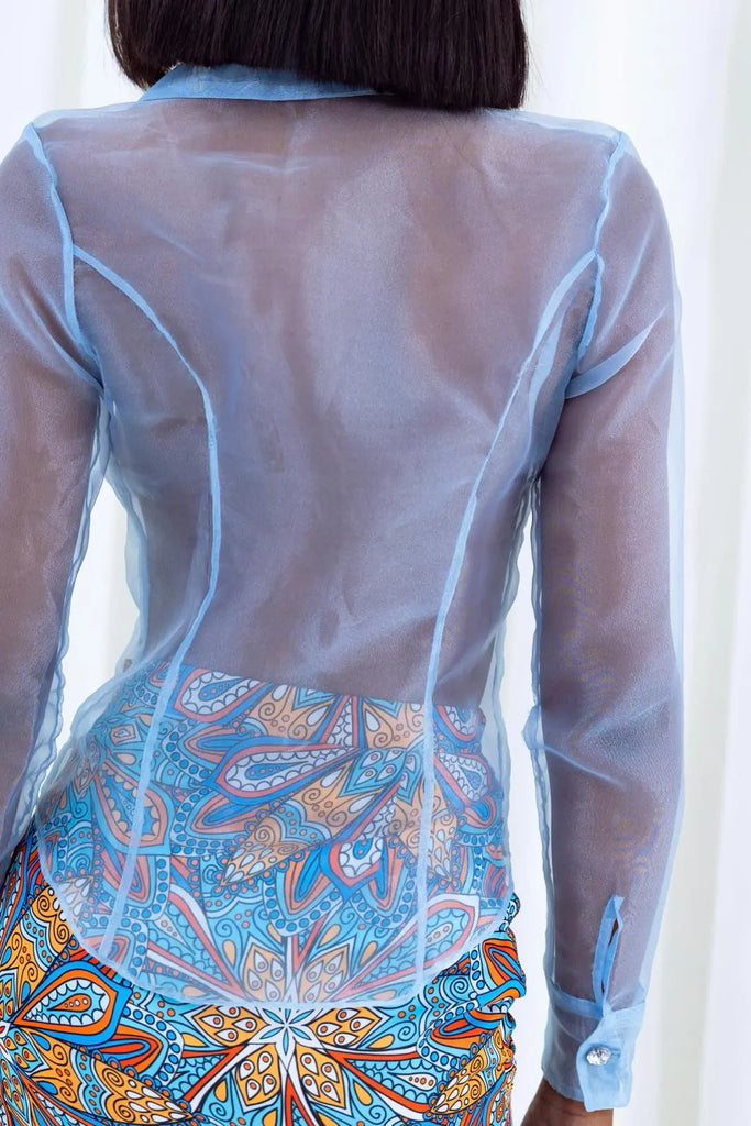 Elegant sheer blue top with vibrant African print design on bottom, showcasing fashionable cultural fusion style.