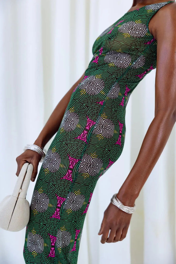 Elegant African print dress in vibrant green and pink hues with intricate spiral patterns, showcasing stylish design and cultural influences.
