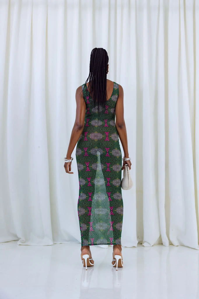 Vibrant African print dress with intricate pattern, worn by a woman with dreadlocks standing in front of a white backdrop.