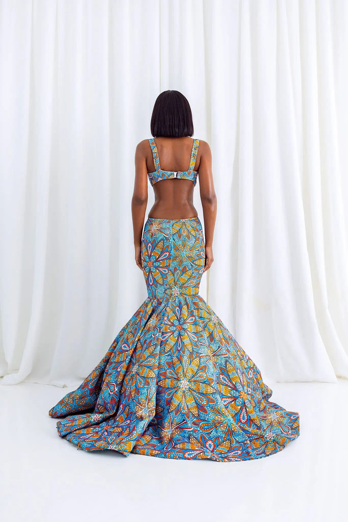 Vibrant African print mermaid gown with intricate floral patterns, featuring a structured bodice and a flowing, dramatic skirt on a female model.