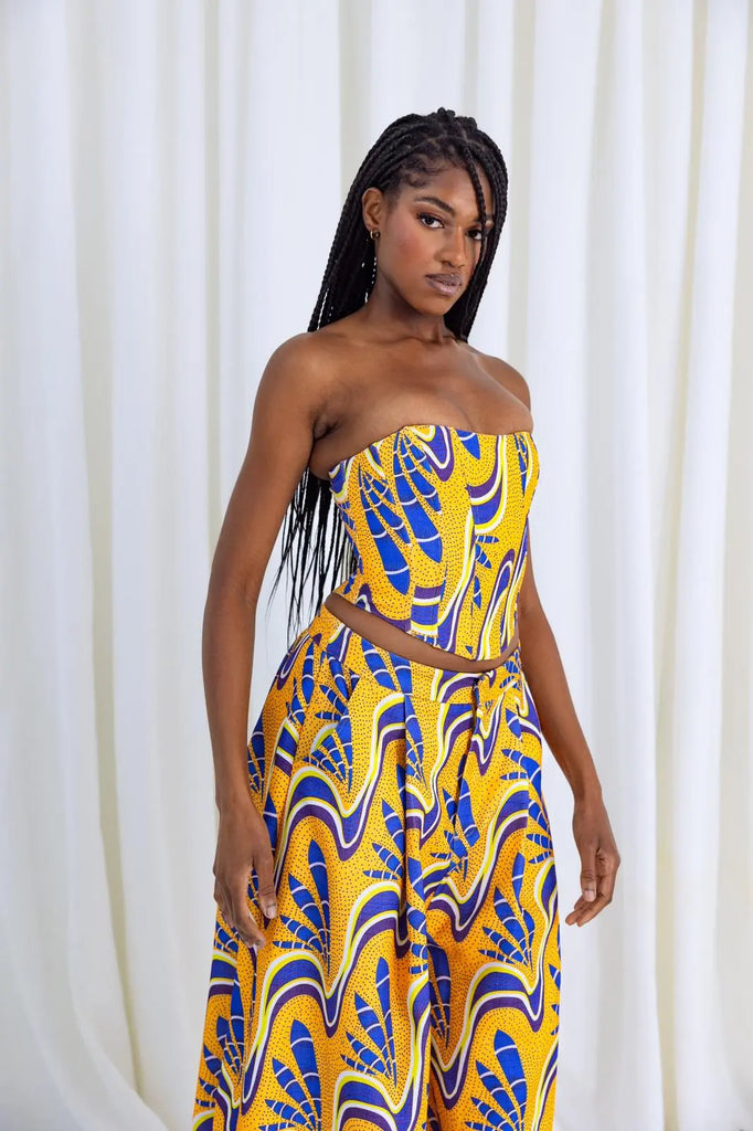 Vibrant African print corset top with geometric patterns, worn by a stylish woman with braided hairstyle against a plain white background.