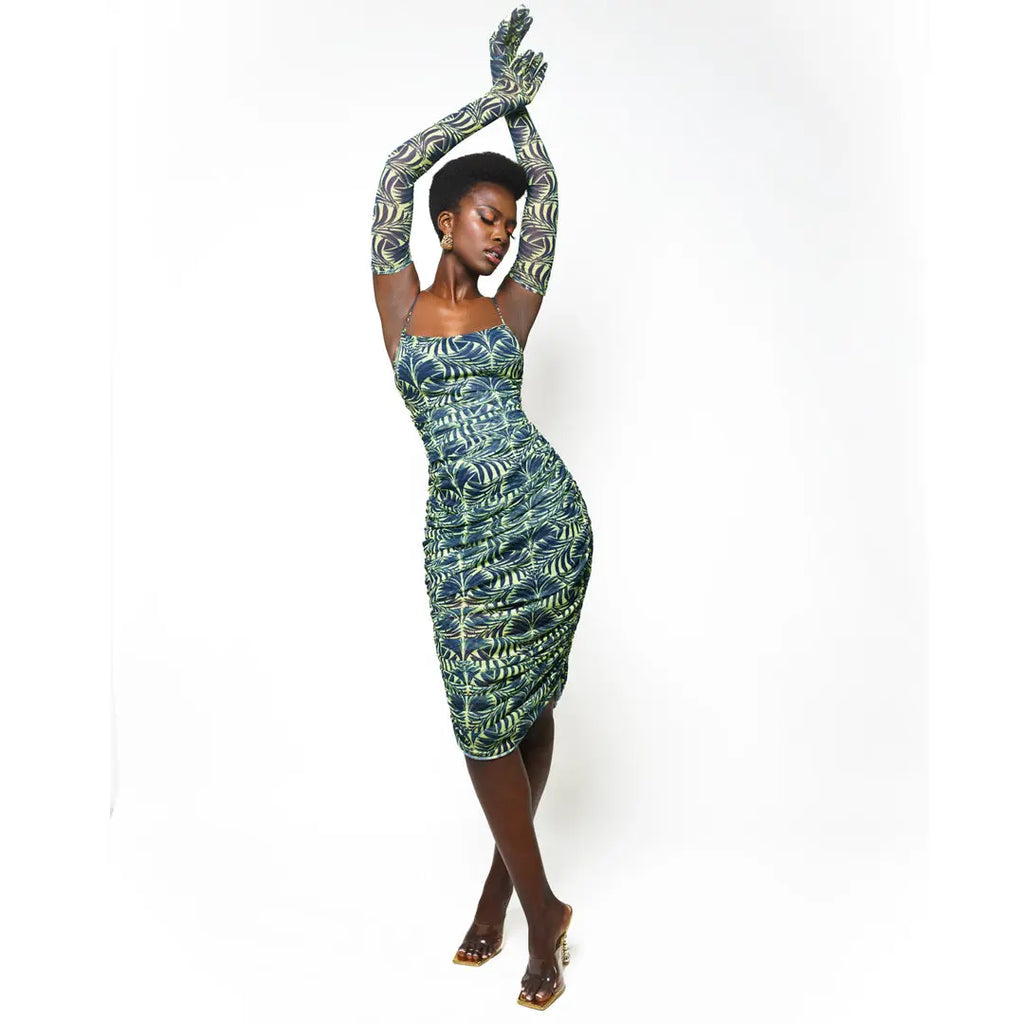 Elegant African print dress with vibrant green and white pattern, featuring a bodycon silhouette and strapless neckline. Model stands confidently, arms raised, showcasing the stylish and form-fitting design.