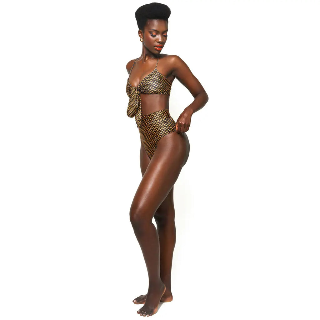 Vibrant gold metallic bikini set highlighting the model's natural beauty and toned physique, featuring a supportive bandeau top and high-waisted bottoms with a trendy criss-cross pattern.